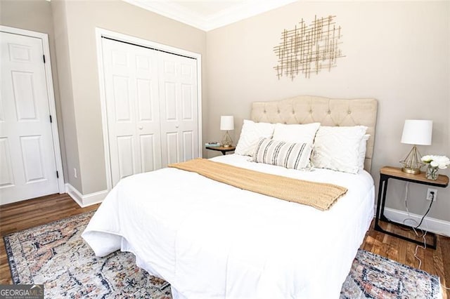 bedroom featuring dark hardwood / wood-style floors, crown molding, and a closet