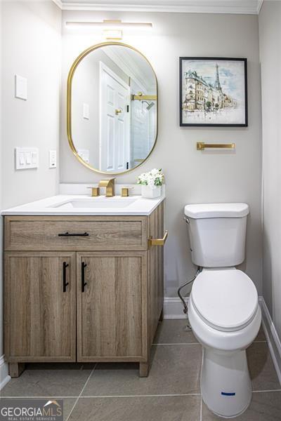 bathroom with tile patterned flooring, vanity, ornamental molding, and toilet