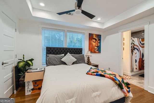 bedroom featuring a raised ceiling, ceiling fan, and dark hardwood / wood-style flooring