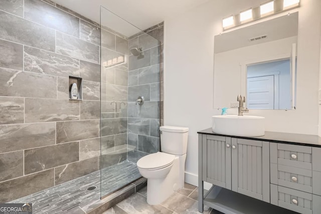 bathroom with vanity, toilet, and a tile shower