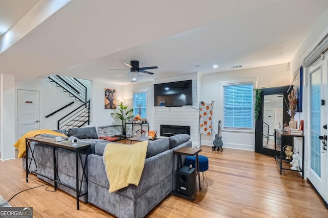 living room with ceiling fan, a fireplace, and light wood-type flooring