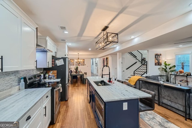 kitchen featuring sink, stainless steel range with electric cooktop, a kitchen island with sink, a breakfast bar, and white cabinets