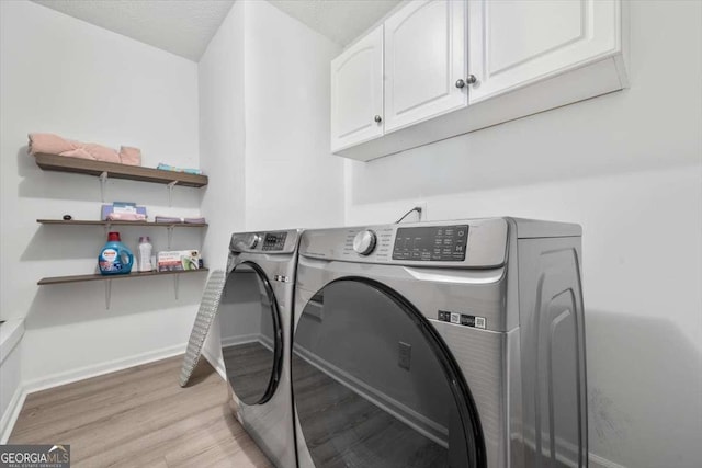 laundry area with cabinets, washing machine and dryer, and light hardwood / wood-style flooring