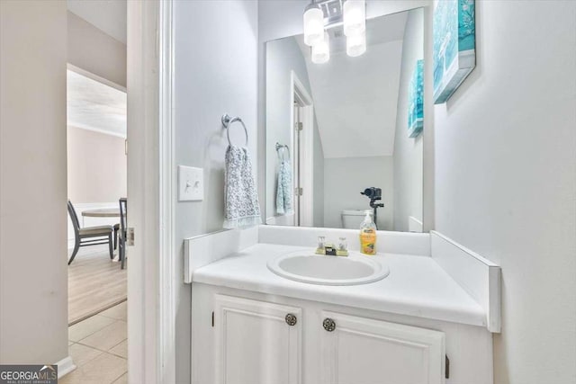 bathroom with toilet, vanity, and tile patterned floors