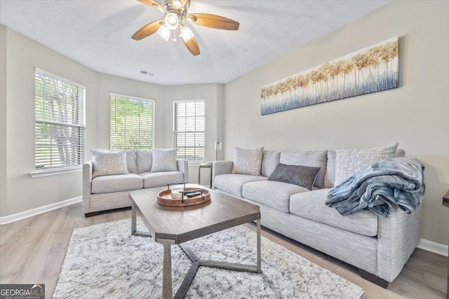 living room with ceiling fan, light hardwood / wood-style floors, and a textured ceiling