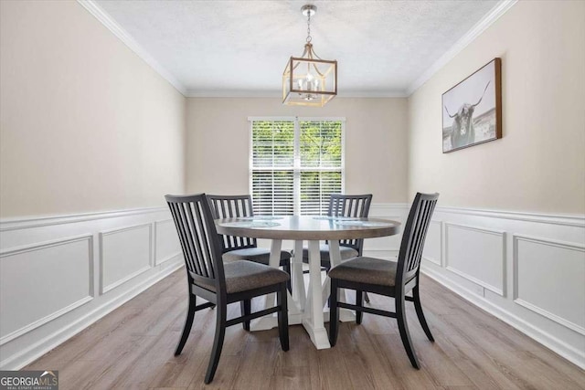 dining room with a textured ceiling, light hardwood / wood-style floors, an inviting chandelier, and ornamental molding