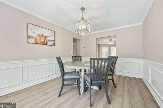 dining area featuring light hardwood / wood-style floors, ceiling fan with notable chandelier, and ornamental molding