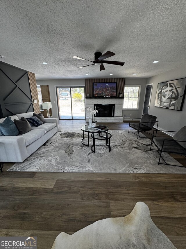 unfurnished living room with ceiling fan, plenty of natural light, a fireplace, and dark hardwood / wood-style flooring