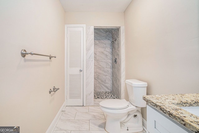 bathroom featuring a tile shower, vanity, and toilet