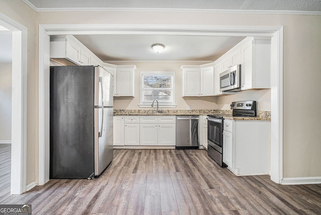 kitchen with white cabinets, stainless steel appliances, light stone counters, and dark hardwood / wood-style floors