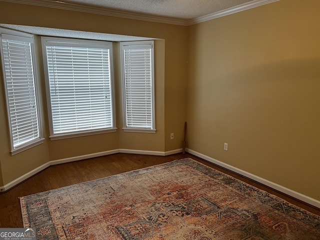 spare room featuring a textured ceiling, wood-type flooring, and crown molding