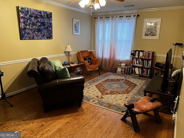 sitting room featuring hardwood / wood-style floors, a textured ceiling, ceiling fan, and crown molding