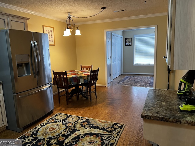 dining area with a chandelier, dark hardwood / wood-style flooring, a textured ceiling, and ornamental molding