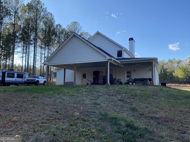 rear view of house featuring a lawn and a carport