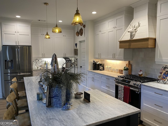 kitchen featuring stainless steel appliances, tasteful backsplash, pendant lighting, white cabinets, and custom range hood