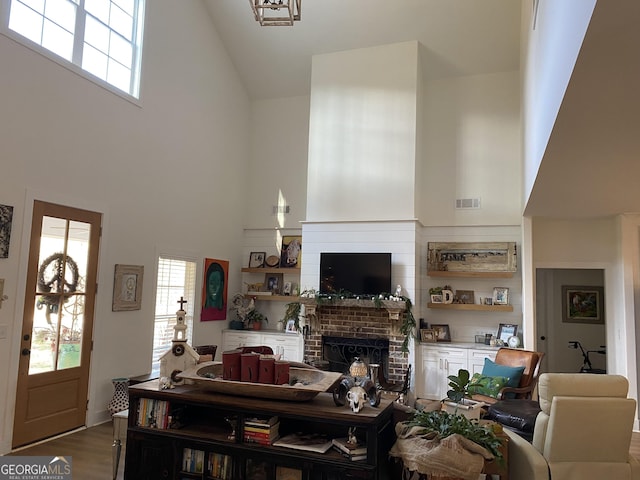 living room with wood-type flooring, a high ceiling, and a brick fireplace