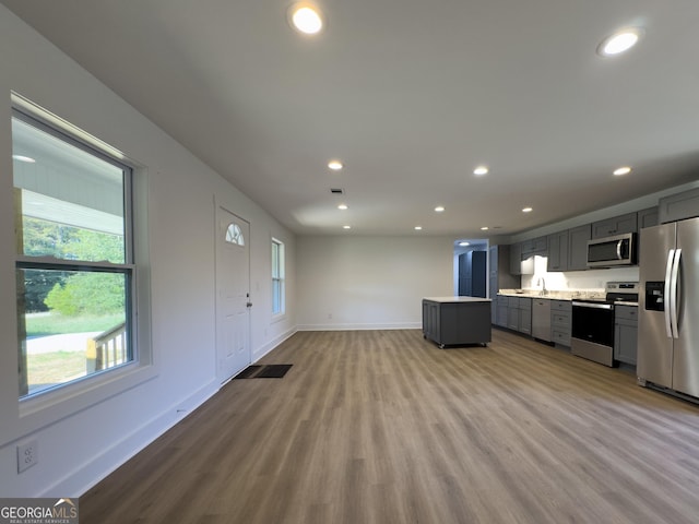 kitchen with light wood-type flooring, stainless steel appliances, gray cabinets, and sink