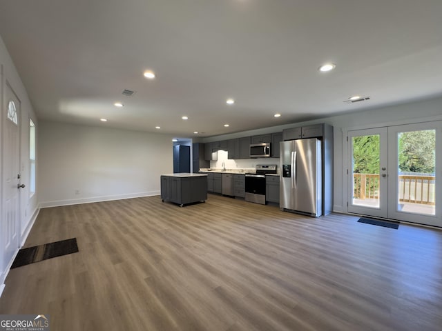 kitchen with a center island, french doors, hardwood / wood-style flooring, gray cabinets, and appliances with stainless steel finishes