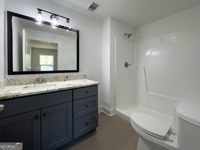 bathroom with a shower, vanity, toilet, and tile patterned flooring