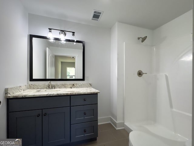 bathroom featuring tile patterned floors, vanity, toilet, and walk in shower