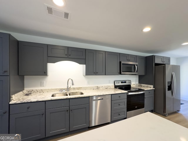 kitchen with gray cabinetry, sink, stainless steel appliances, and light hardwood / wood-style floors