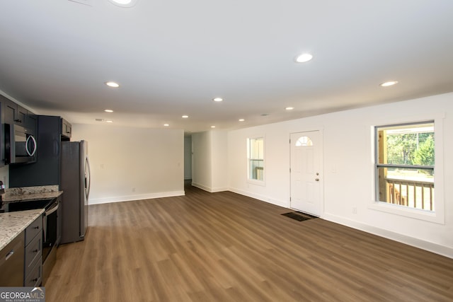 interior space with light stone countertops, dark hardwood / wood-style floors, and appliances with stainless steel finishes