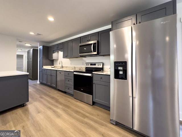 kitchen featuring light wood-type flooring, stainless steel appliances, gray cabinets, and sink