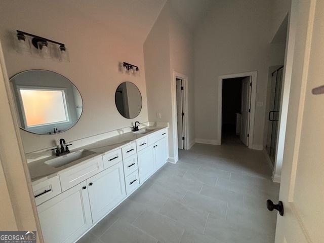 bathroom with double vanity, a stall shower, a high ceiling, and a sink