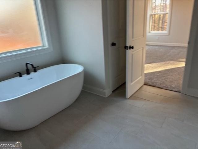 bathroom featuring a soaking tub and baseboards