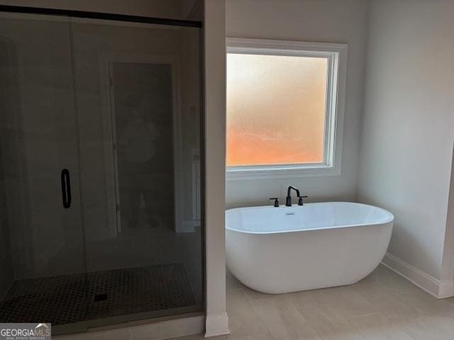 full bath featuring a freestanding tub, a shower stall, and baseboards