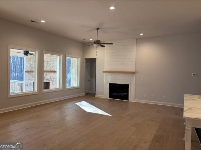 unfurnished living room with a fireplace, recessed lighting, visible vents, wood finished floors, and baseboards