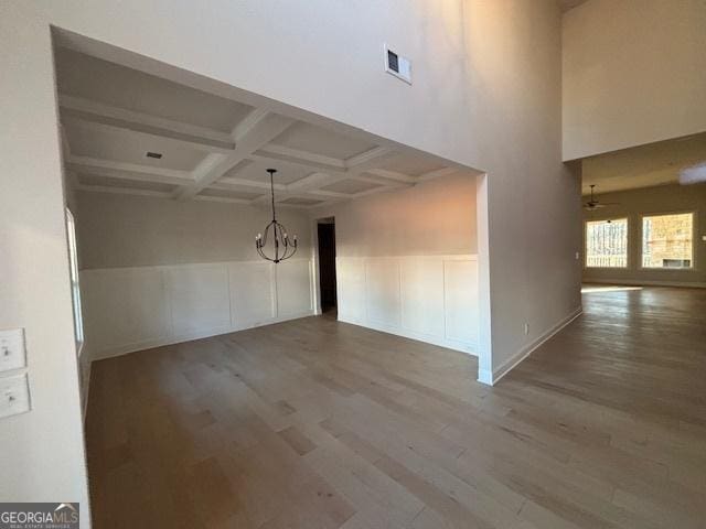 interior space with beam ceiling, visible vents, wood finished floors, a chandelier, and coffered ceiling