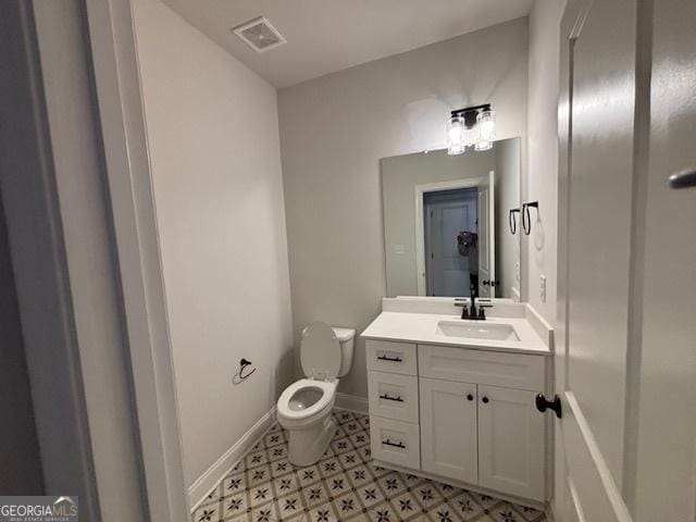 bathroom featuring toilet, vanity, visible vents, and baseboards