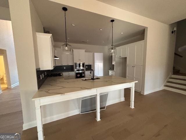 kitchen with white cabinets, a peninsula, light stone countertops, stainless steel appliances, and a sink