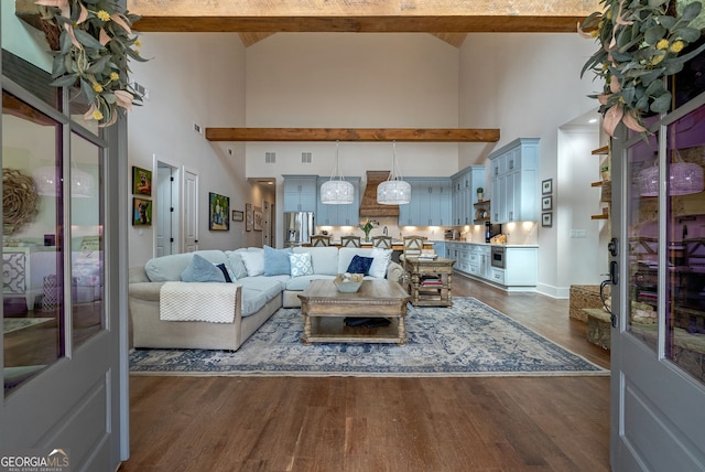 living room featuring beam ceiling, dark hardwood / wood-style flooring, and a high ceiling