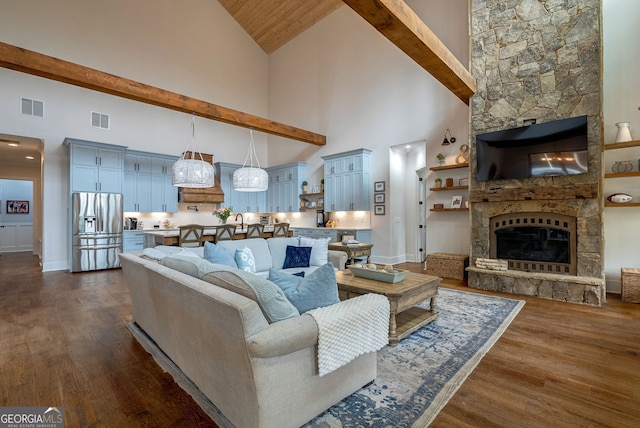 living room featuring a stone fireplace, dark hardwood / wood-style flooring, high vaulted ceiling, and beamed ceiling