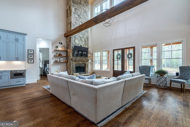 living room with a towering ceiling, dark hardwood / wood-style floors, and a stone fireplace