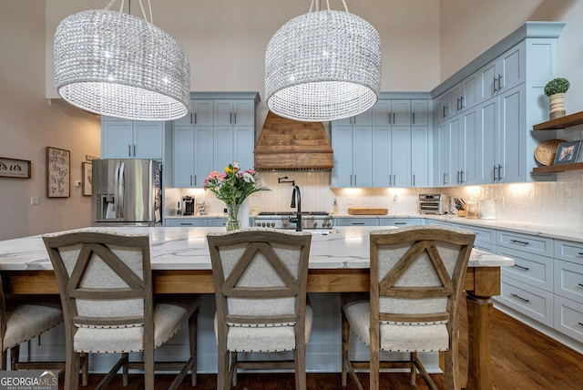 kitchen featuring backsplash, a center island with sink, stainless steel appliances, and an inviting chandelier
