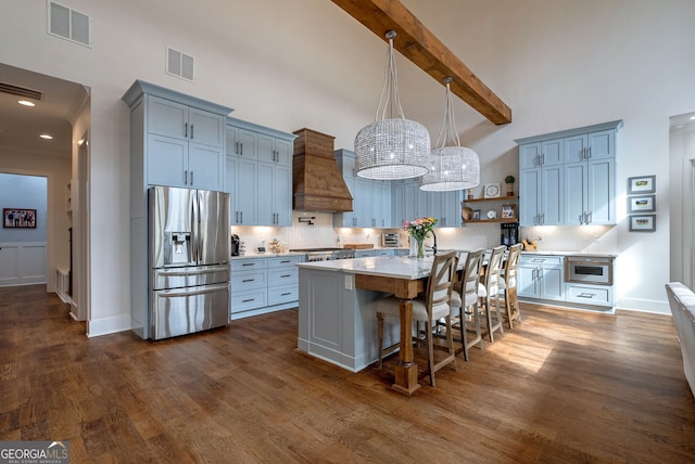 kitchen with custom exhaust hood, a center island, decorative backsplash, stainless steel fridge, and beam ceiling