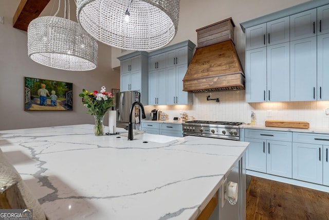 kitchen with premium range hood, light stone countertops, decorative light fixtures, and appliances with stainless steel finishes