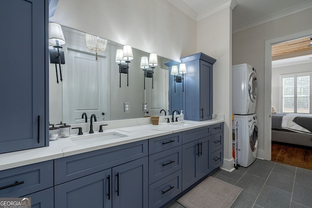 bathroom with tile patterned flooring, a notable chandelier, stacked washer and dryer, vanity, and ornamental molding