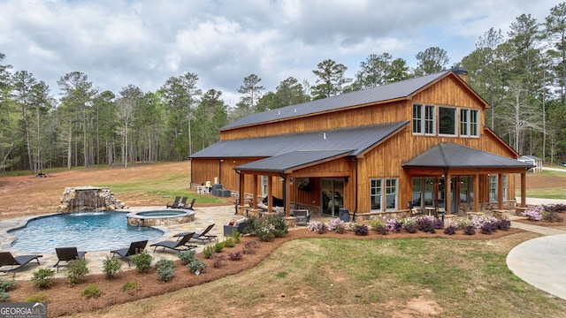 back of house featuring a lawn, a pool with hot tub, a patio area, and pool water feature
