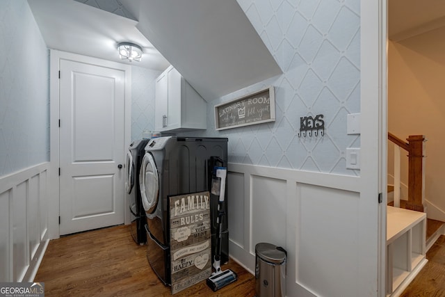 clothes washing area with washer and clothes dryer, cabinets, and hardwood / wood-style flooring