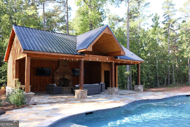 view of swimming pool featuring a patio and an outdoor stone fireplace