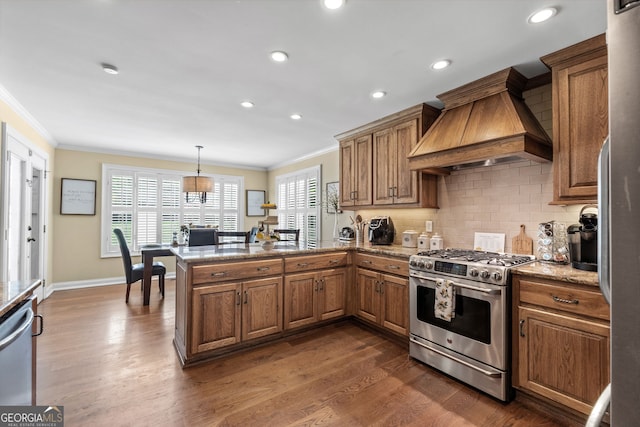 kitchen with premium range hood, pendant lighting, kitchen peninsula, appliances with stainless steel finishes, and dark hardwood / wood-style flooring