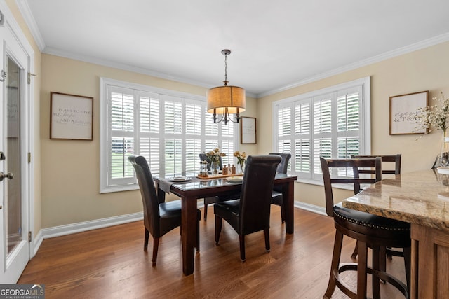 dining area featuring dark wood-type flooring, an inviting chandelier, and crown molding