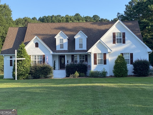 new england style home featuring covered porch and a front yard