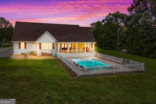 back house at dusk featuring a fenced in pool, a sunroom, a yard, and a patio