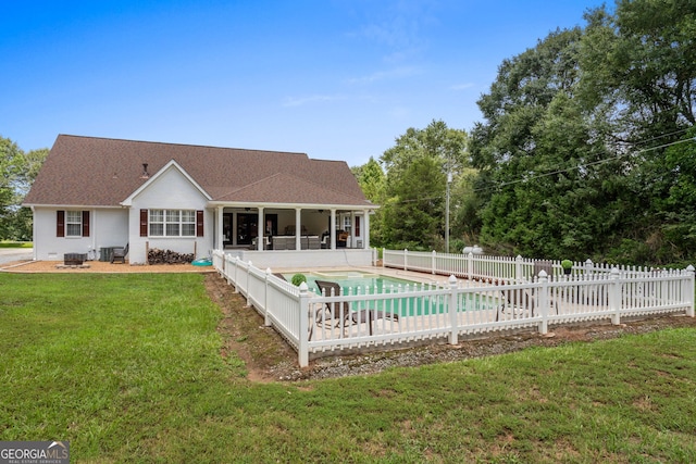 rear view of property with a sunroom, a patio area, a fenced in pool, an outdoor fire pit, and a yard