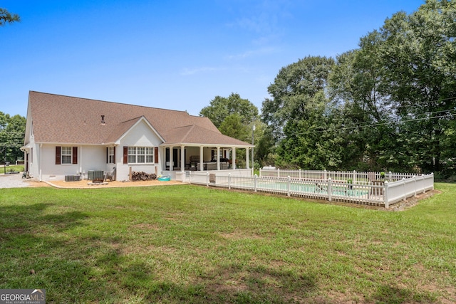 rear view of house with a fenced in pool, a yard, and central AC